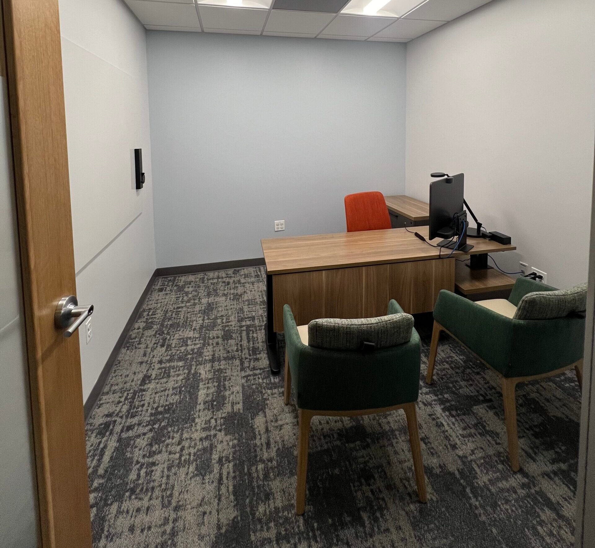 office with an L desk, monitor, and multiple chairs